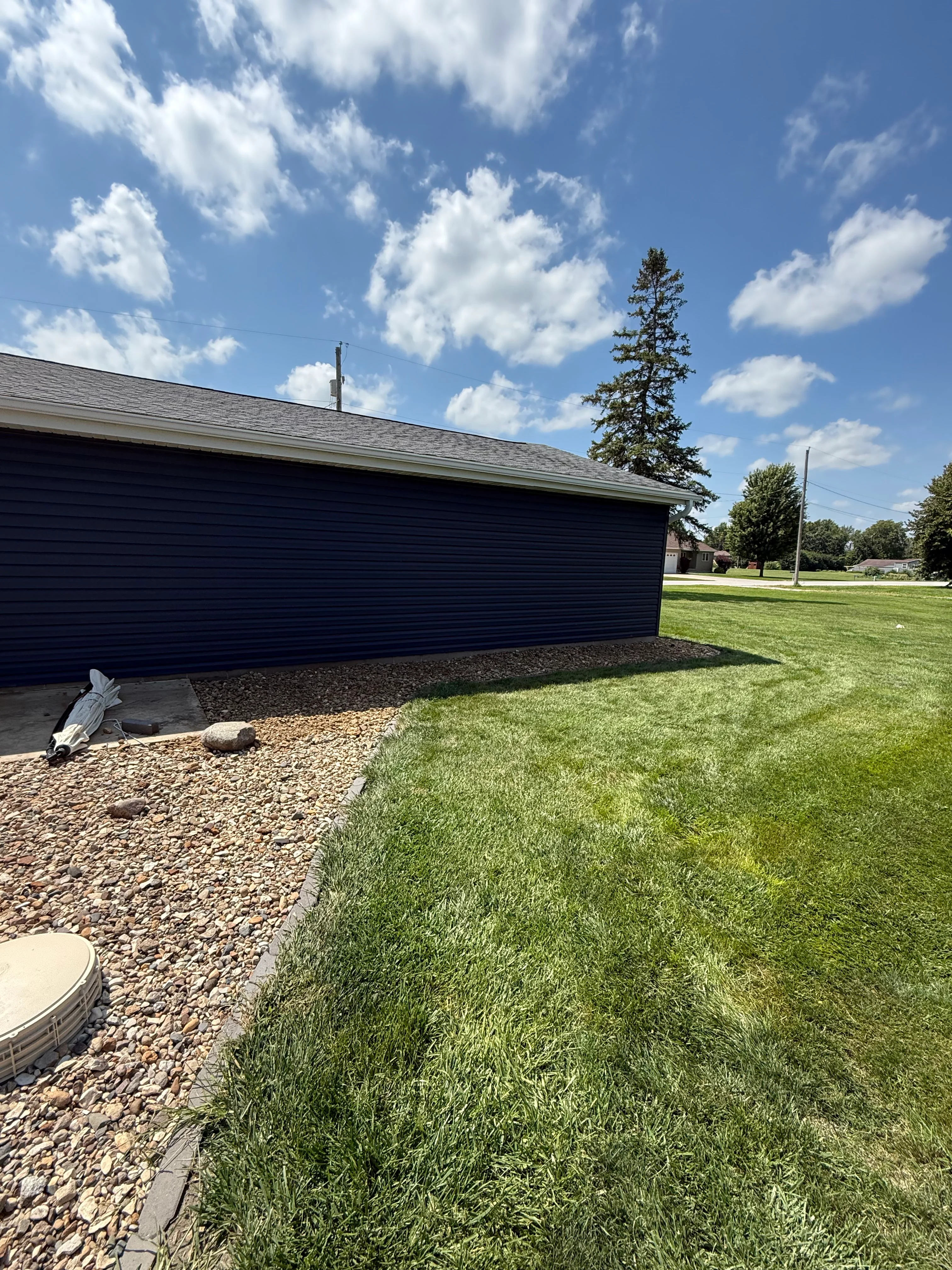New sod lawn installation with river rock borders and landscape edging around residential property