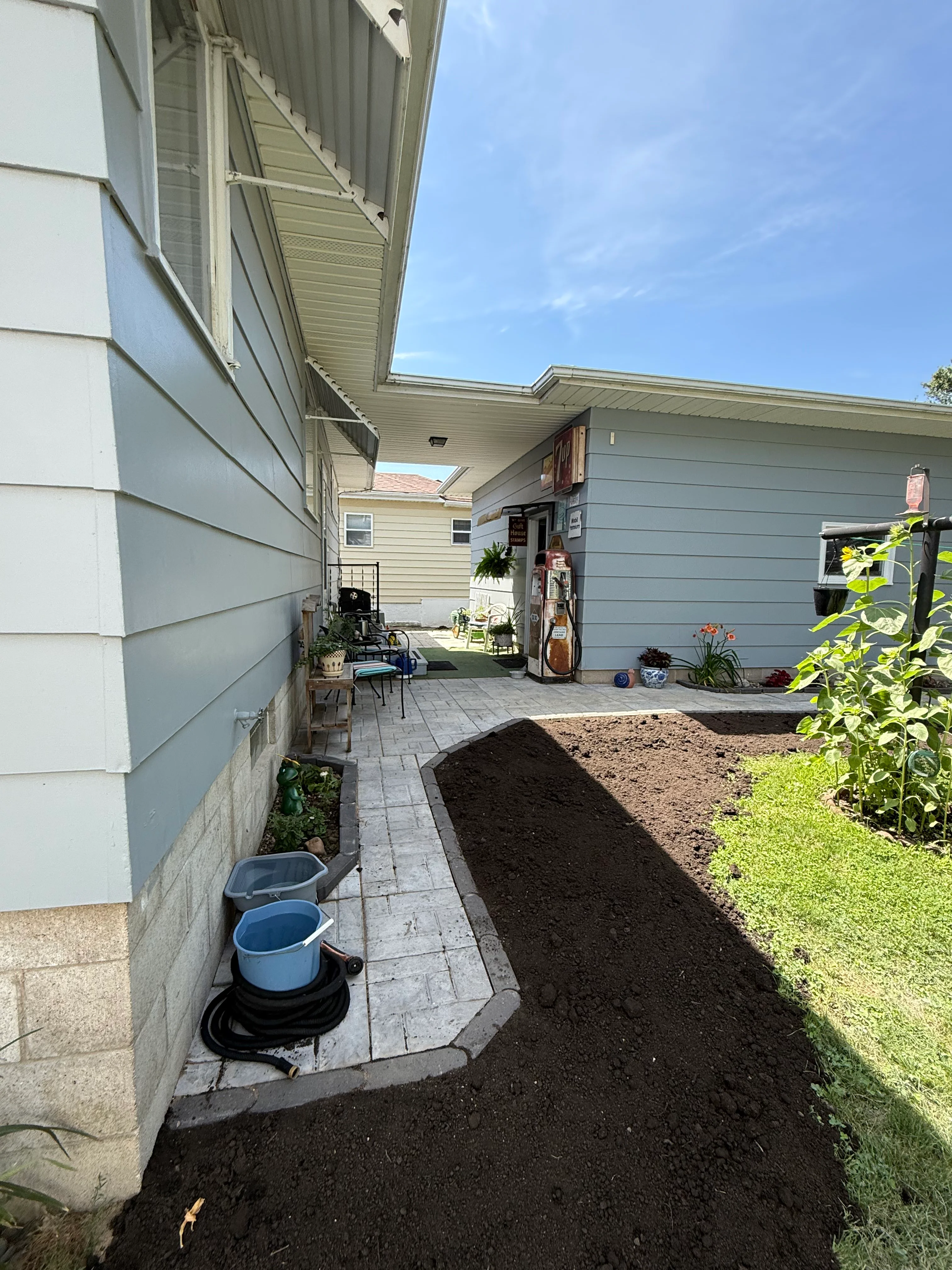 Newly installed gray paver patio with landscape beds and plantings in residential side yard