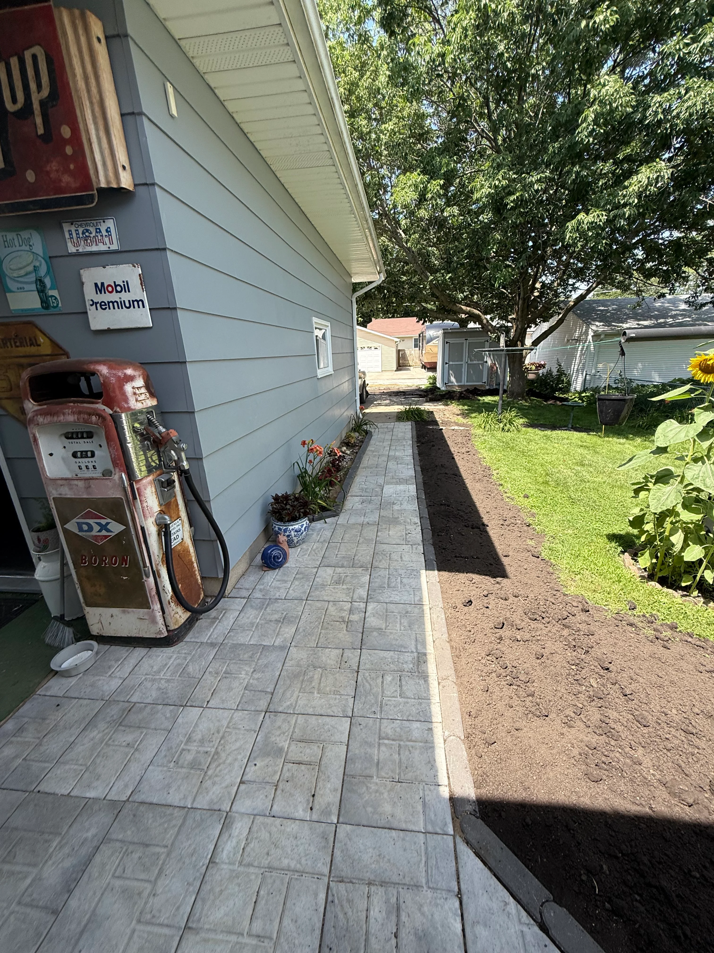 Gray paver pathway alongside residential home with new mulch beds and lawn edging